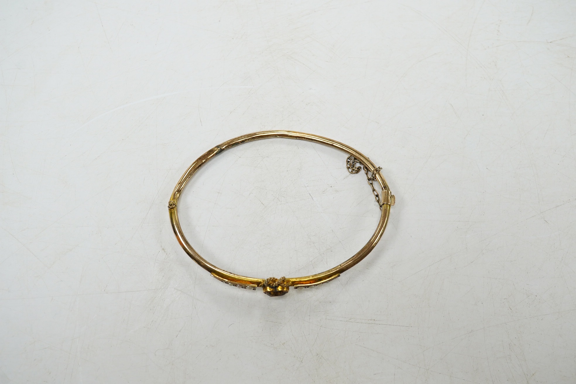 A Victorian yellow metal, citrine and seed pearl set hinged bangle, with heart shaped citrine, interior diameter 62mm, gross weight 4.6 grams, with fitted leather box. Condition - poor